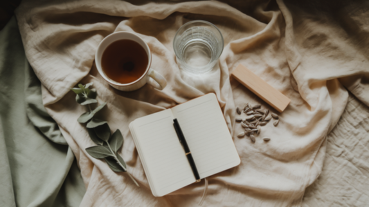 A calm flat-lay — tea, a glass of water and an open notebook with a pen: things to reach for instead of a cigarette
