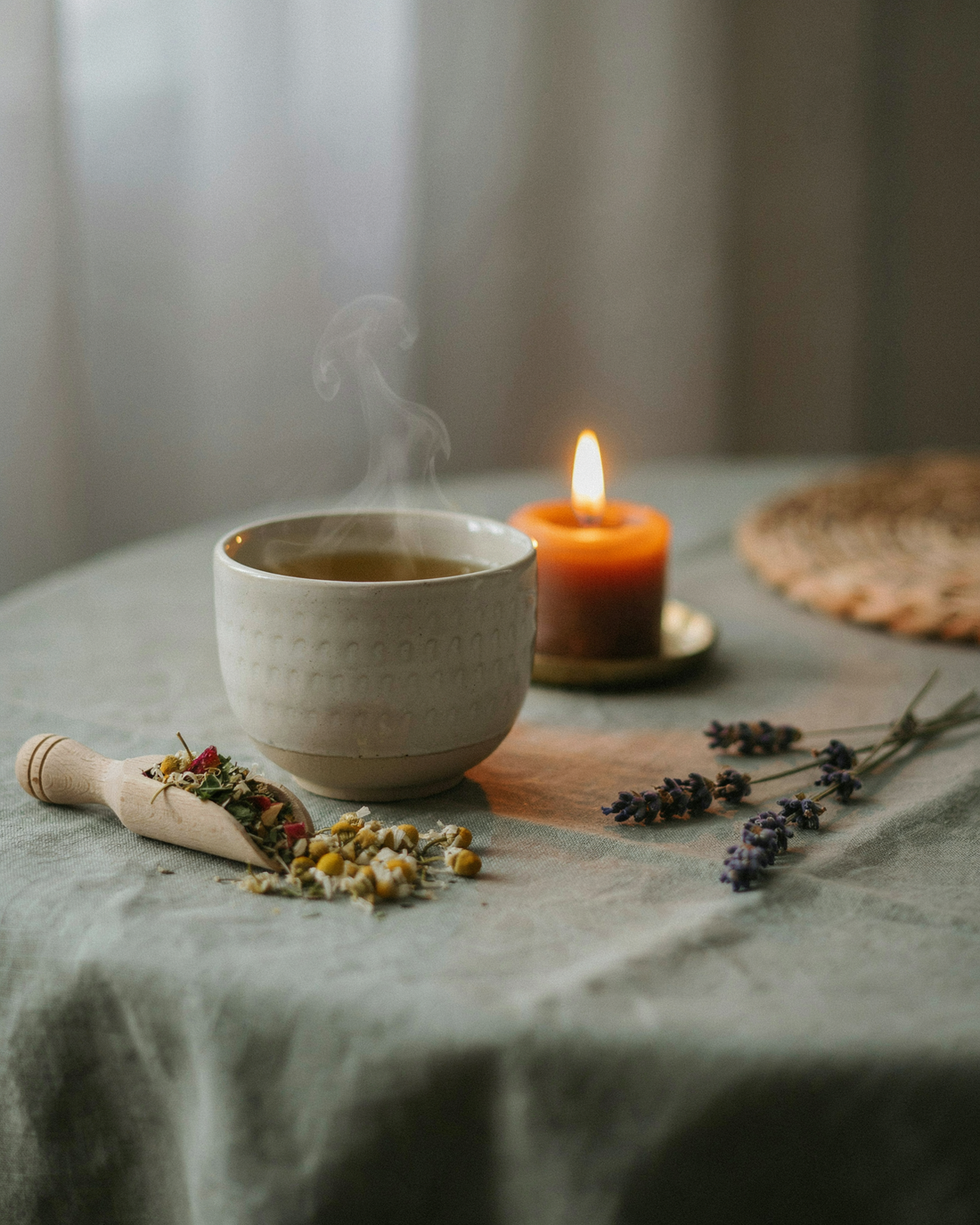 A steaming mug of calming herbal tea by candlelight with chamomile and lavender