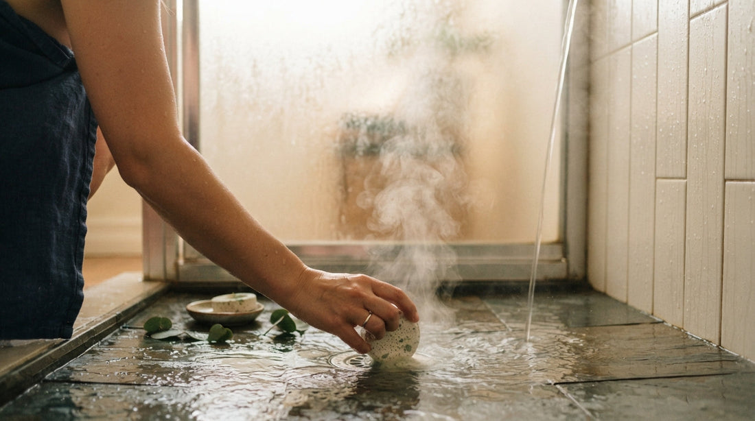 A hand placing an aromatherapy shower steamer on a steamy shower floor