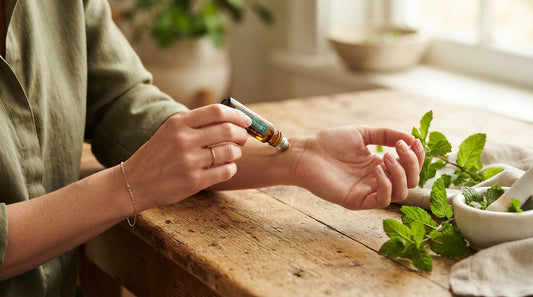 Applying a peppermint roll-on next to fresh mint sprigs on a table