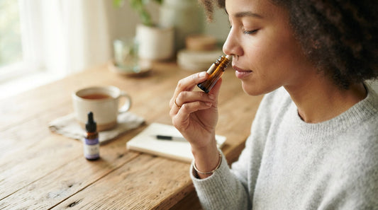 A woman breathing in slowly from a pocket aromatherapy inhaler at a sunny table
