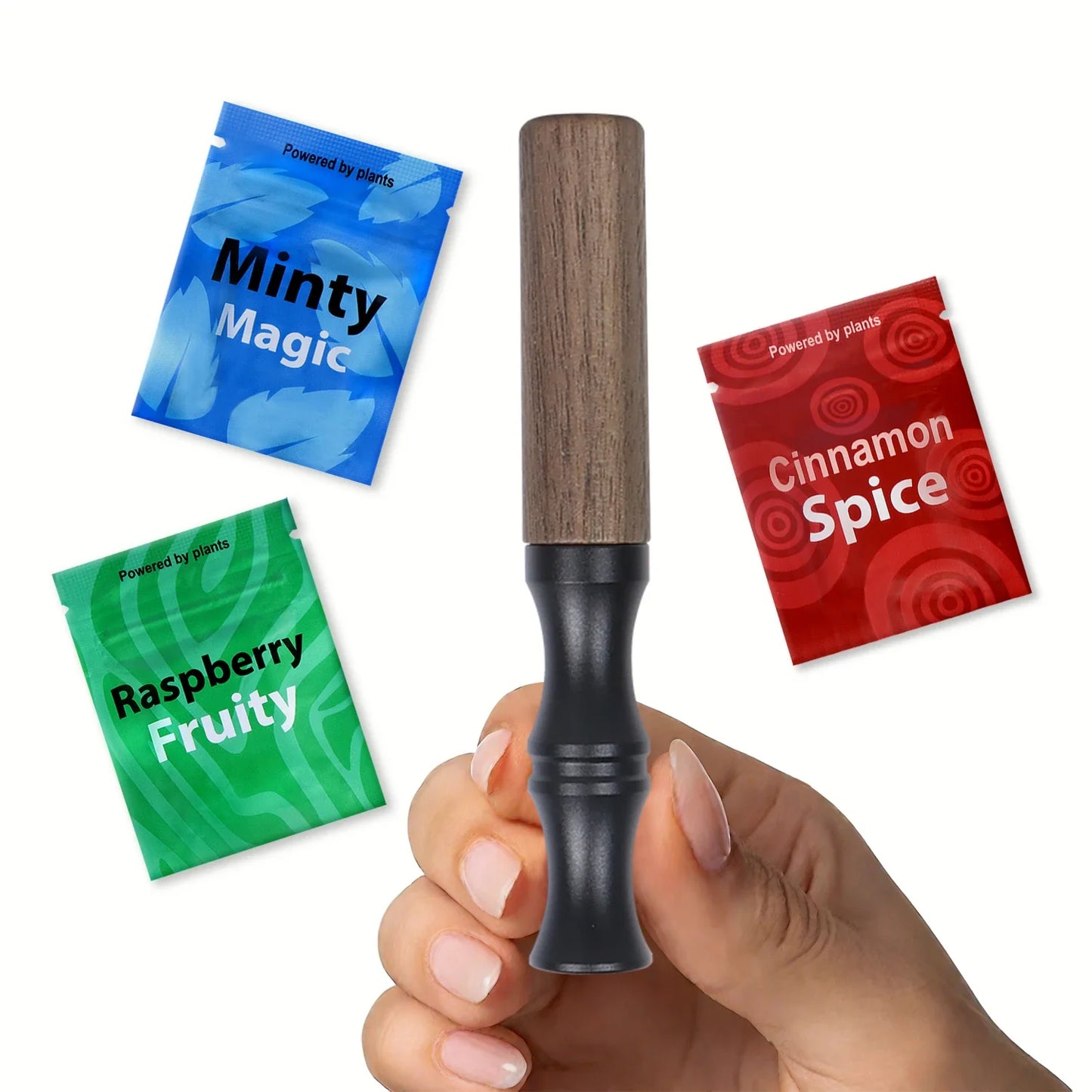 Nicotine-free wooden inhaler stick with wood top and black body held in hand, shown with Minty Magic, Cinnamon Spice and Raspberry Fruity Powered by plants flavor bags